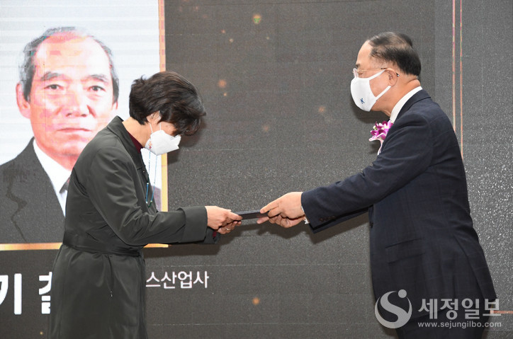 모범납세자 이기철 에이스산업사 대표이사(대리참석 자녀 이은희 씨. 좌측)가 금탑산업훈장을 전수받고 있다. [기획재정부 제공]