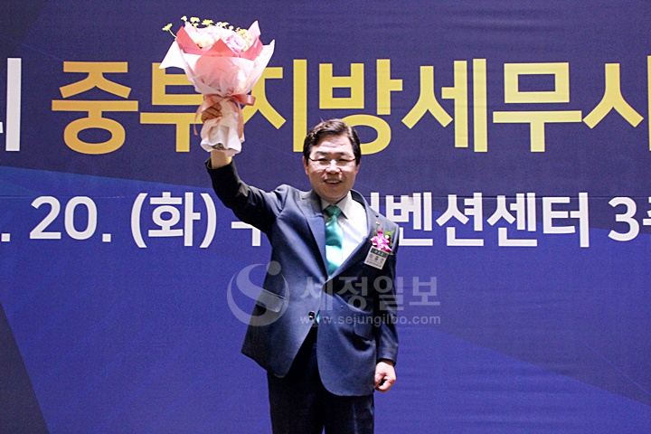 꽃다발을 들어올리며 기뻐하고 있는 이중건 중부지방세무사회장.