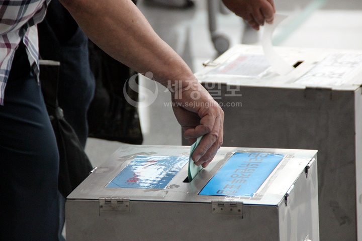 자신이 지지하는 후보에게 소중한 한표를 꾹 눌러 찍은후 투표함에 넣고있다.