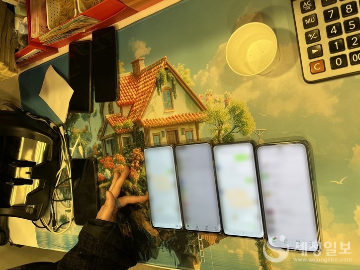 환전상 단속직원이 한국과 중국간의 환치기 송금에 이용한 환전상의 핸드폰을 살펴보고 있다. [관세청 제공]