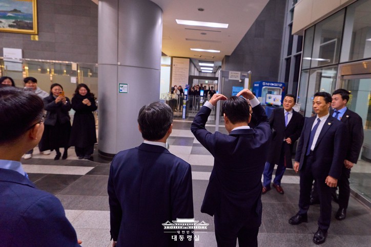 이재명 대통령이 국세청을 방문한 후 청사를 떠나며 환송하는 직원들을 항해 하트를 표시하며 대통령의 마음을 전하고 있다. [사진: 대통령실]